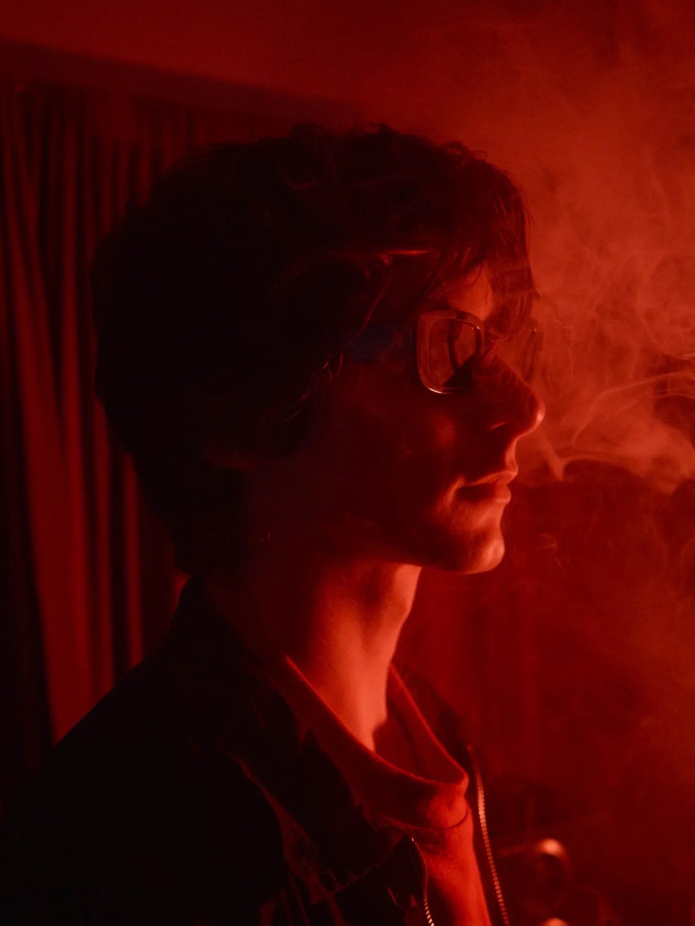 Side profile in red light with smoke